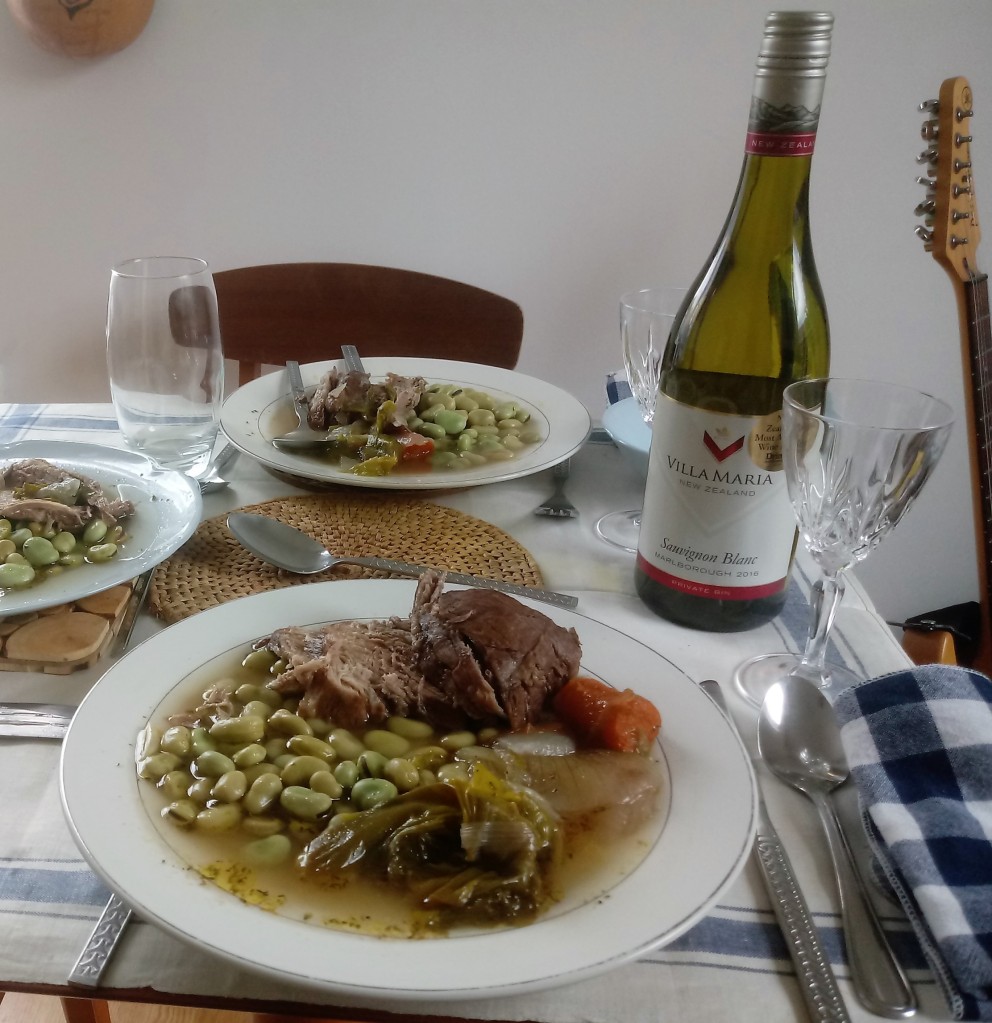 Plates of judd mat gaardebounen on a table with white wine, stainless steel cutlery and wine glasses